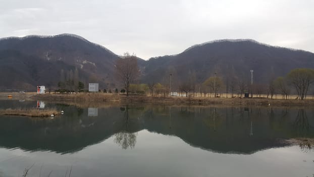 View of beautiful scene of river water and green trees on large hills on a sunny day with blue sky in background. A lovely landscape with breathtaking view over the horizon .
