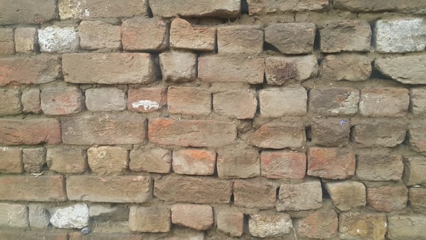 Closeup texture of red brick wall. A background of a weathered old exterior brick wall in the sunshine.