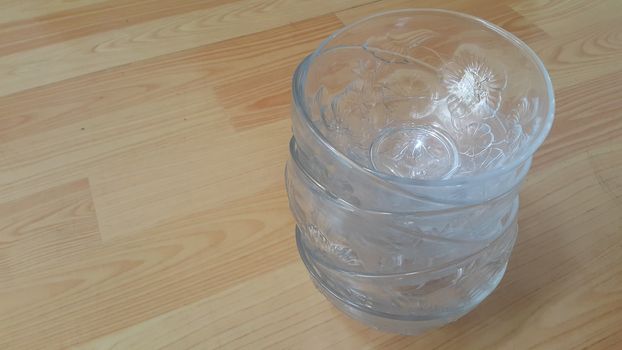 Top view of empty white glass bowls on a wooden floor. Glass bowl with flowers made on its wall