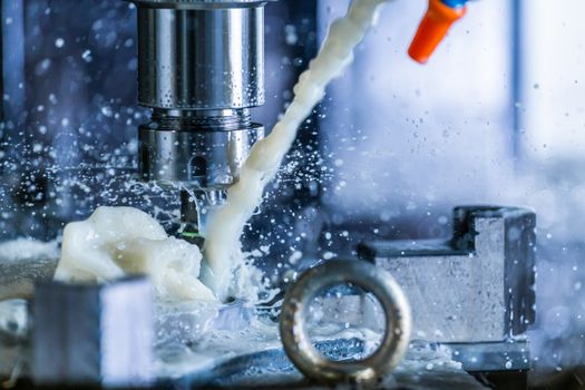 A process of vertical cnc steel milling with external water coolant streams and splashes. Fast shutter speed for motion freezing.
