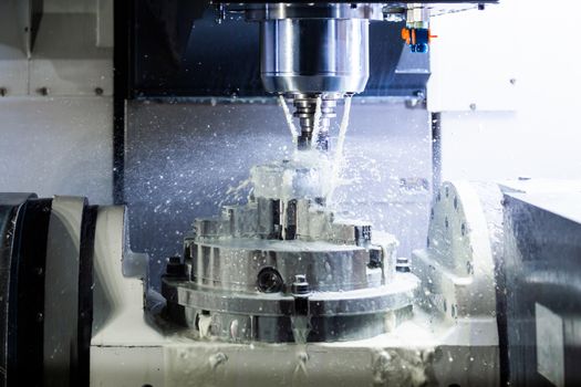 a process of industrial wet milling in 5-axis cnc machine with coolant flow under pressure and freezed streams and splashes.