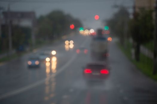 Defocused picture of evening city street car traffic after rain - view from road.