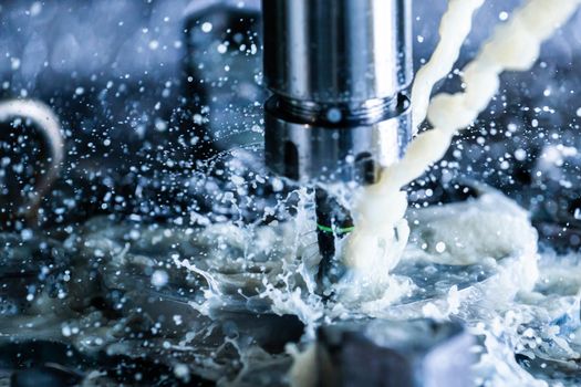 A process of vertical cnc steel milling with external water coolant streams, splashes and a lot of metal chips. Fast shutter speed for motion freezing.