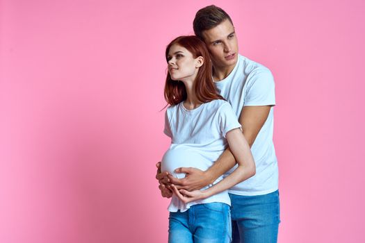 pregnant mom and happy father on pink background Young family waiting for baby. High quality photo