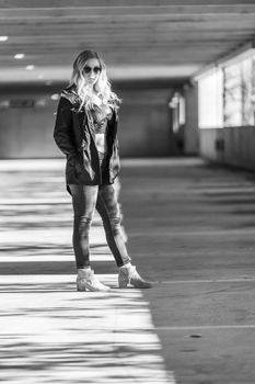 A gorgeous blonde model poses in a parking deck on an autumn day