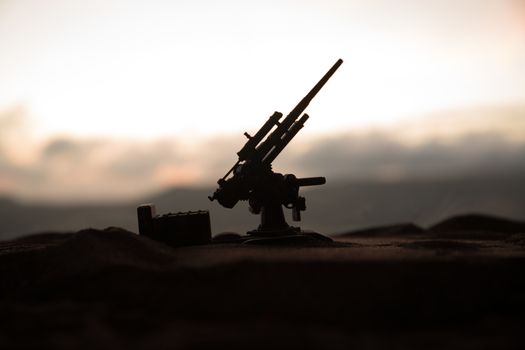 Silhouette of anti-aircraft cannon on battlefield during sunset time. Creative artwork table diorama. Selective focus. , World War Soldiers Silhouettes Below Cloudy Skyline at sunset.