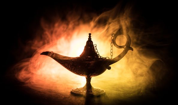 Antique Aladdin arabian nights genie style oil lamp with soft light white smoke, Dark background. Lamp of wishes concept