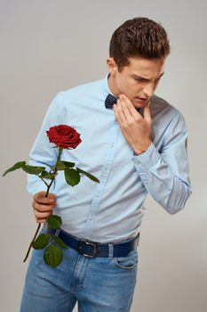 Handsome man with red rose blue shirt bow tie light background cropped view. High quality photo