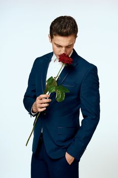 A man in a suit with a rose in his hands a gift date light background. High quality photo