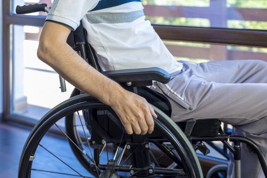 Man in wheelchair at home or in office. Focus on his hand.