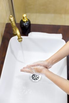 Woman washing and disinfecting hands with soap and hot water as part of coronavirus prevention and protection protocols; stop spreading covid-19 hygiene protocols