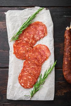 Chorizo, spanish traditional sausage cut to slices on dark wooden background, topview.