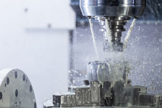 a process of industrial wet milling in 5-axis cnc machine with coolant flow under pressure and freezed streams and splashes.