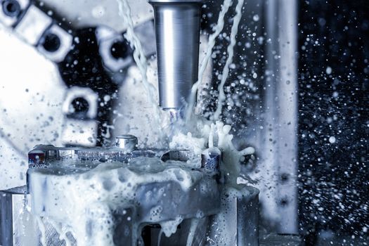 A process of vertical cnc steel milling with external water coolant streams and splashes. Fast shutter speed for motion freezing.