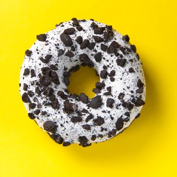 chocolate donut with white glaze isolated on yellow background, close up flat lay