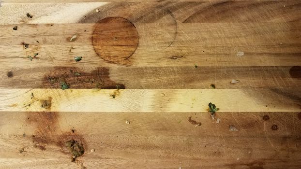 dirty wood cutting board with bits of food and circular stain