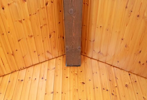 Rustic house ceiling with wide wooden beam support, pine wood