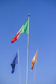 Italian and European flag under blue sky in summer