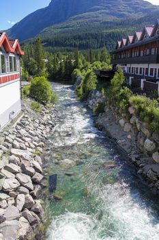 Flowing beautiful turquoise river water between houses in Hemsedal, Viken, Buskerud, Norway.