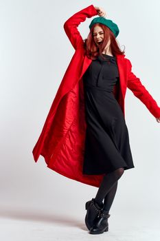emotional woman in a red coat and with a hat in full growth on a light background black boots pose model. High quality photo