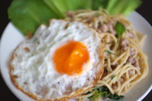 Close up view , Spaghetti stir fried with Thai Basil spicy sauce with Fried egg  , fusion Thai style