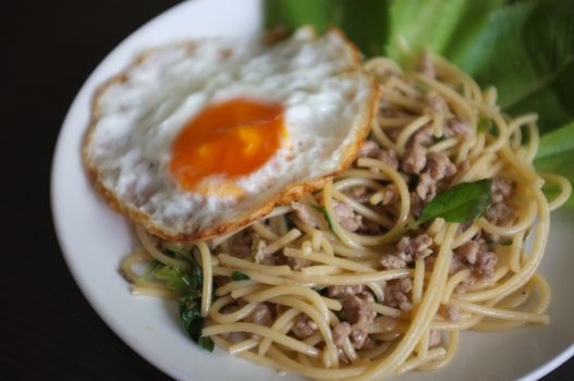 Close up view , Spaghetti stir fried with Thai Basil spicy sauce with Fried egg  , fusion Thai style