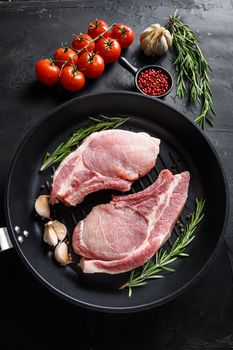 Pork belly Farm fresh cutlet with oil and spices for grill and ingredients for cooking on black skillet over dark black slate background.