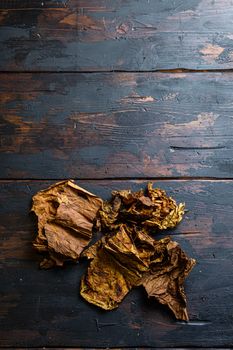dry leafs tobacco Nicotiana tabacum and tobacco leaves on old wood planks table dark top view space for text.