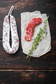 Fuet, dry cured sausage cut to slices on dark wooden background.