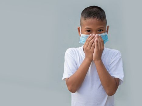 Boy wearing a protective mask And put his hand on his mouth On a gray background. New normal concept.