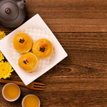 Moon cake for Mid-Autumn Festival, delicious beautiful fresh mooncake on a plate over dark wooden background table, top view, flat lay layout design concept.