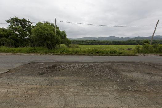 Very bad road in Russia. The asphalt road is all in holes in the middle of the forest