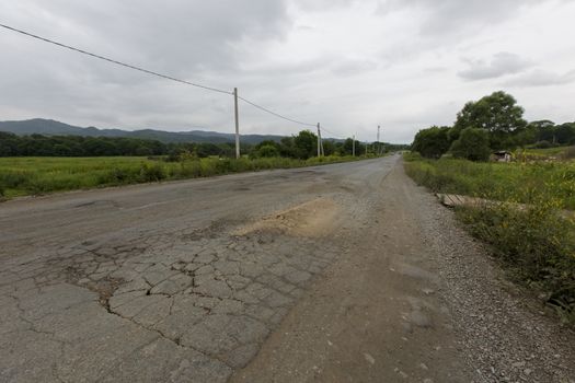 Very bad road in Russia. The asphalt road is all in holes in the middle of the forest