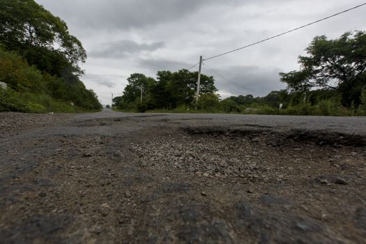 Very bad road in Russia. The asphalt road is all in holes in the middle of the forest