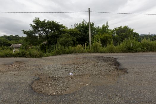 Very bad road in Russia. The asphalt road is all in holes in the middle of the forest