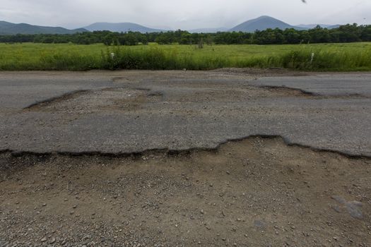 Very bad road in Russia. The asphalt road is all in holes in the middle of the forest