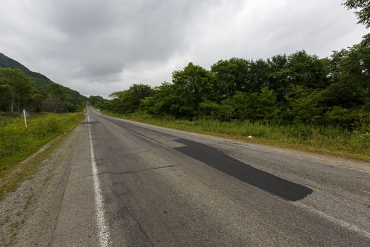 Very bad road in Russia. The asphalt road is all in holes in the middle of the forest