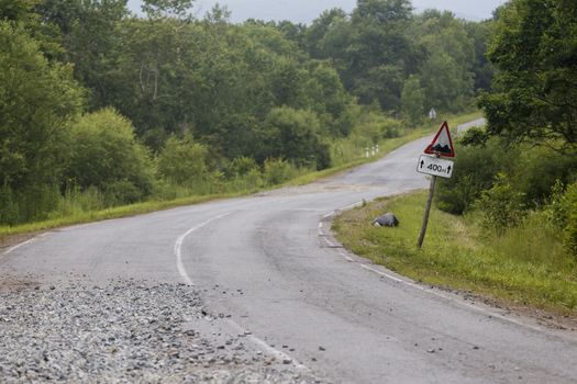 Very bad road in Russia. The asphalt road is all in holes in the middle of the forest