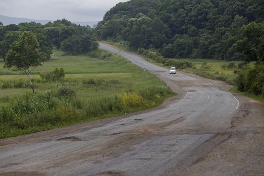 Very bad road in Russia. The asphalt road is all in holes in the middle of the forest