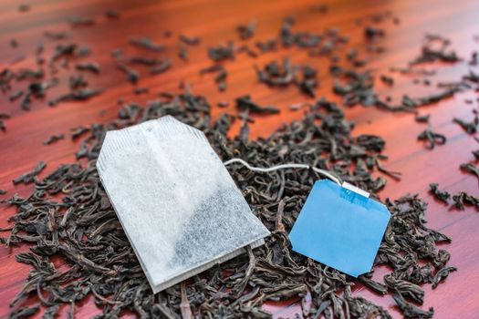 A packet of black long tea lies on the leaves of custard tea