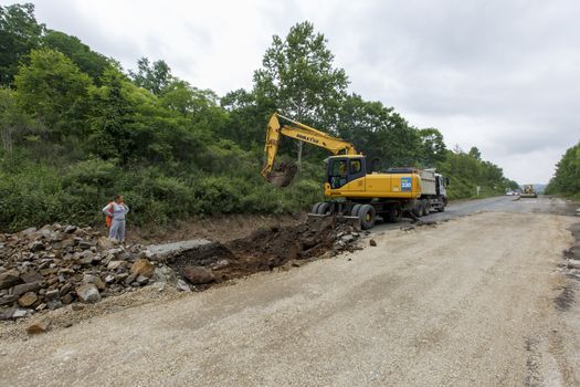 Repair of a bad road. Workers pave a bad road in a forest in Russia.