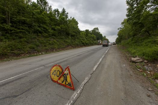 Repair of a bad road. Workers pave a bad road in a forest in Russia.