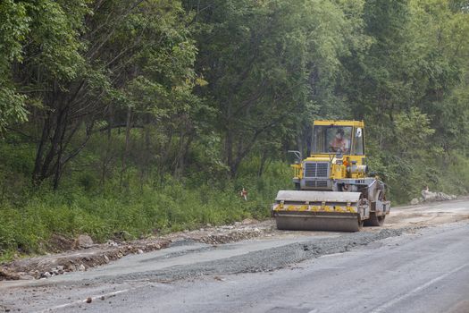 Repair of a bad road. Workers pave a bad road in a forest in Russia.