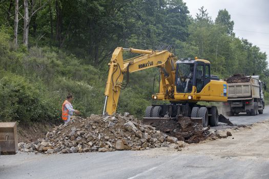 Repair of a bad road. Workers pave a bad road in a forest in Russia.