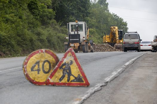 Repair of a bad road. Workers pave a bad road in a forest in Russia.