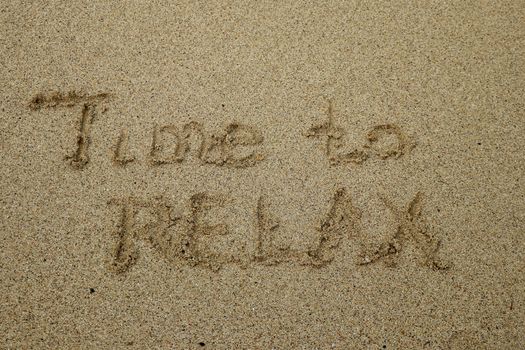 time to relax, concept written on sandy beach.