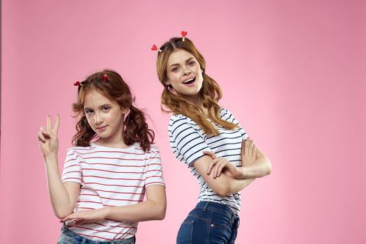 Cheerful mom and daughter lifestyle joy striped shirts family pink background. High quality photo