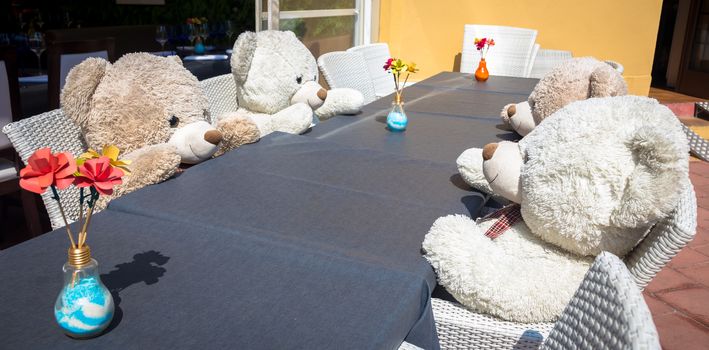 A group of Teddy Bears sitting at the a table and ready for a lunch or a meeting