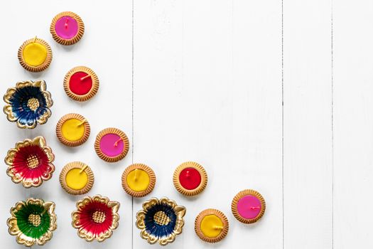 Happy Diwali - Clay Diya lamps lit during Dipavali, Hindu festival of lights celebration. Colorful traditional oil lamp diya on white wooden background