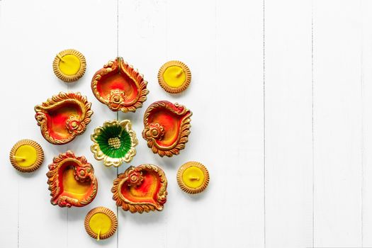 Happy Diwali - Clay Diya lamps lit during Dipavali, Hindu festival of lights celebration. Colorful traditional oil lamp diya on white wooden background